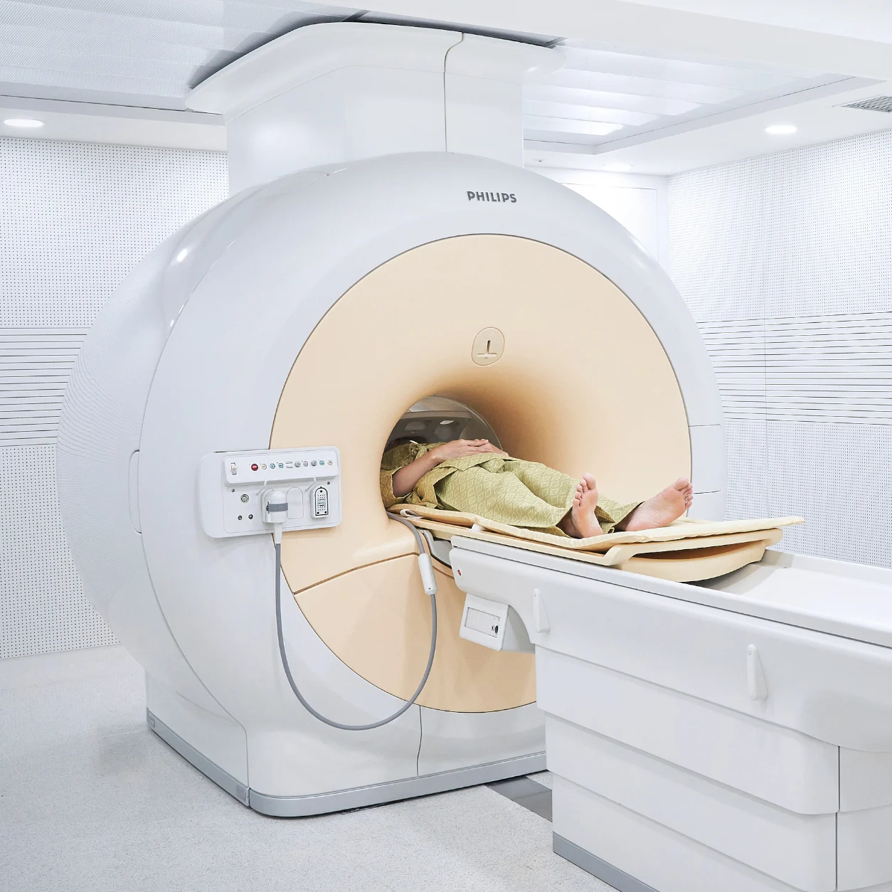 검사복을 입은 환자가 MRI 장비 안으로 들어가는 검사대에 누운 장면