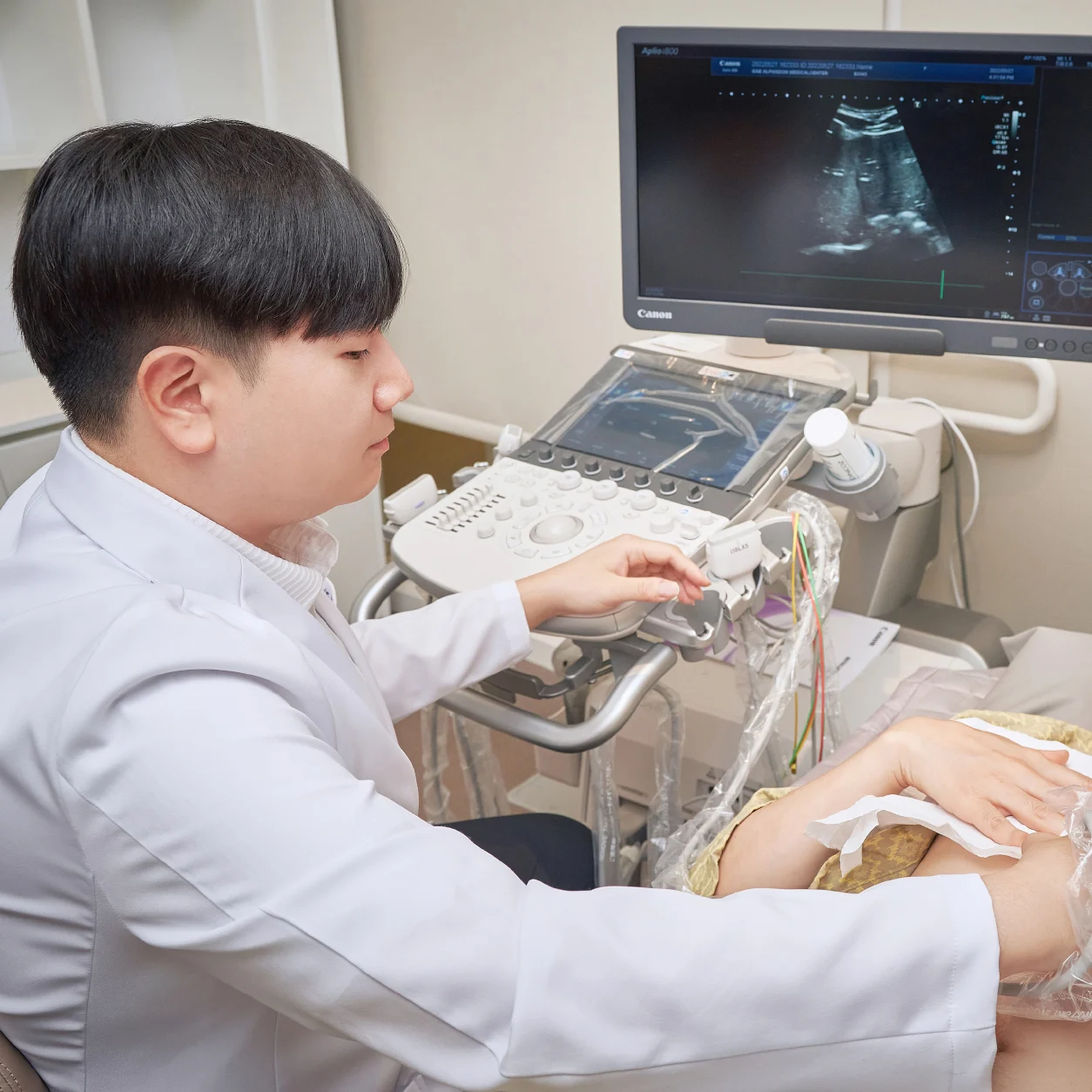 흰 가운을 입은 의료진이 환자의 복부에 탐촉자를 대고 초음파 화면을 보는 장면